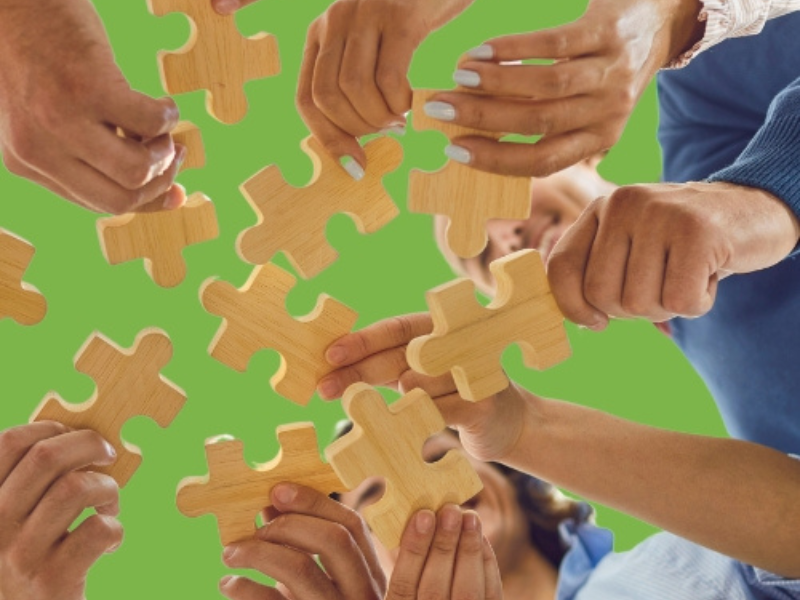 Menschen halten Puzzleteile zusammen.