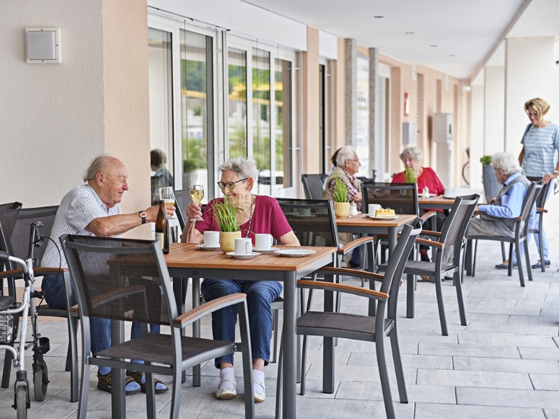 Rentner am Tisch sitzend stoßen an.