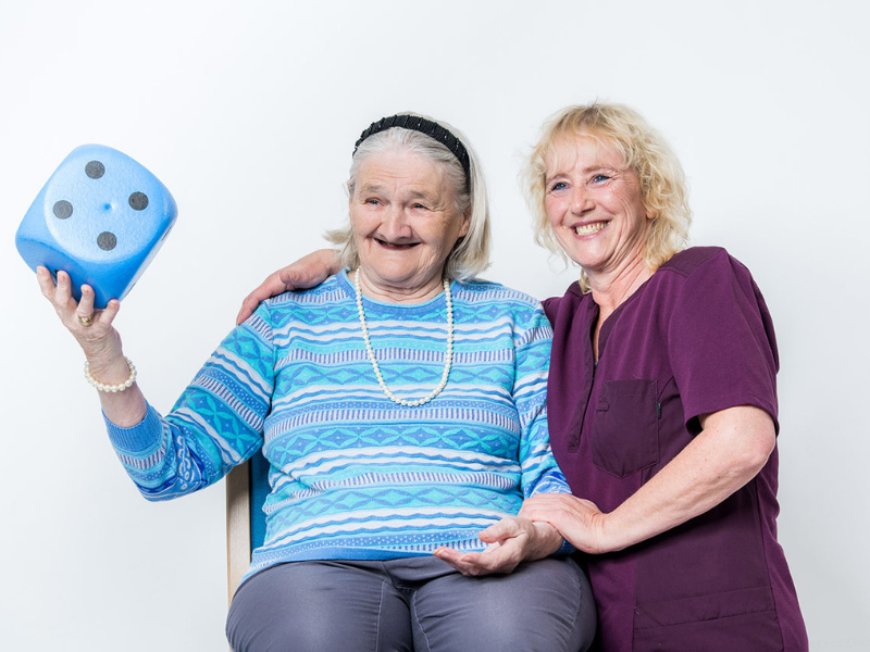 Glückliche Menschen posieren mit Würfel in der Hand.